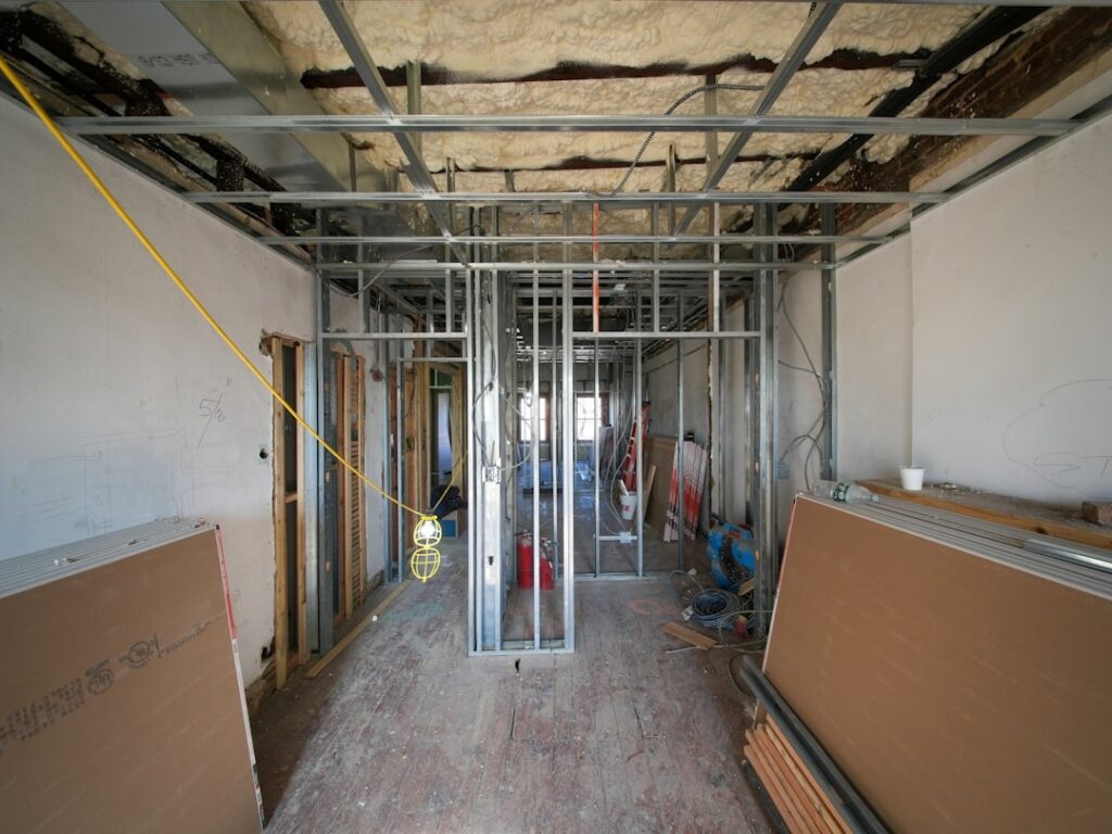 Construction workers renovate an interior space with exposed wall studs.